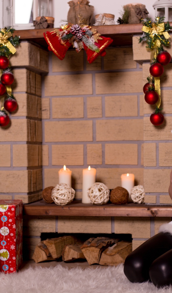 Девочка сидит у камина с подарком на новый год