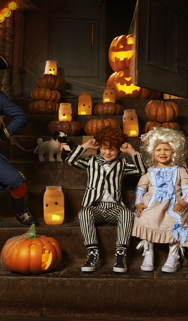Дети в костюмах на Хэллоуин с тыквами на ступеньках