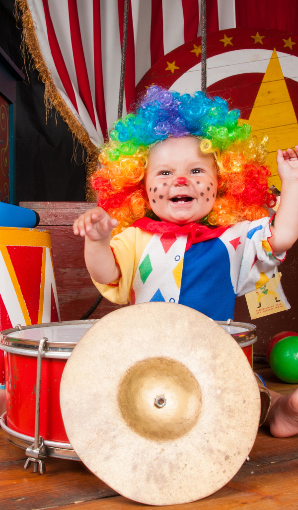 Маленький ребенок в костюме клоуна с музыкальными инструментами