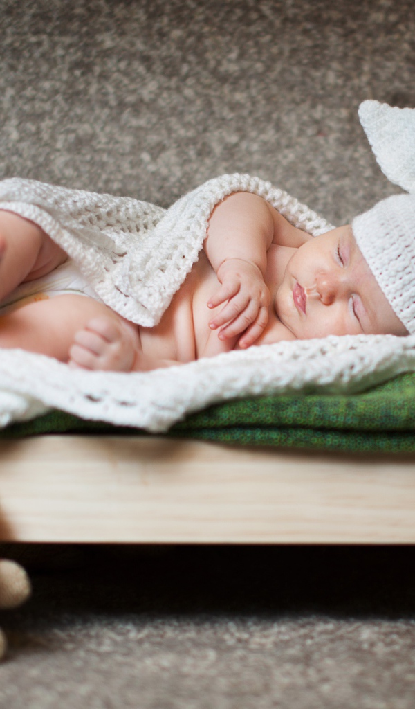 Маленький ребенок в костюме зайца на кровати 