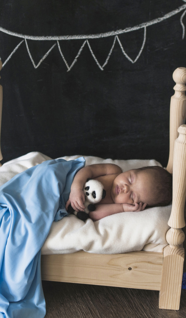 Маленький ребенок спит в деревянной кровати 