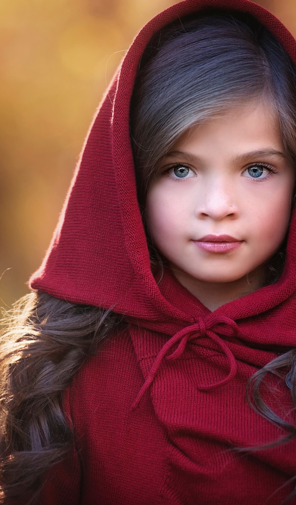 Маленькая красивая голубоглазая девочка с красным капюшоном на голове