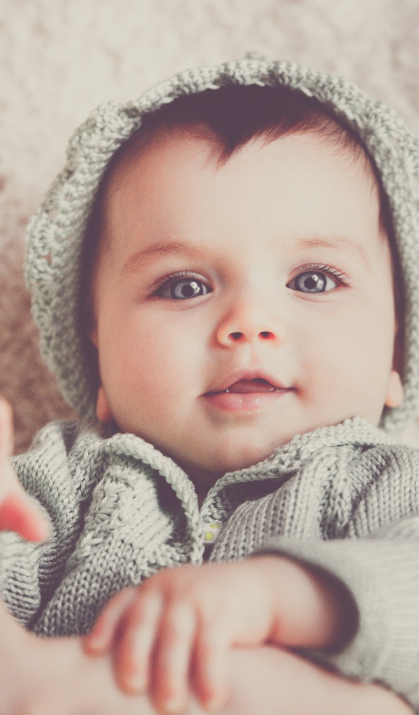 Маленький голубоглазый улыбающийся ребенок в вязаном костюме