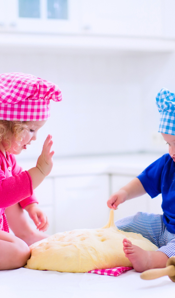 Маленькие мальчик и девочка на кухне с тестом