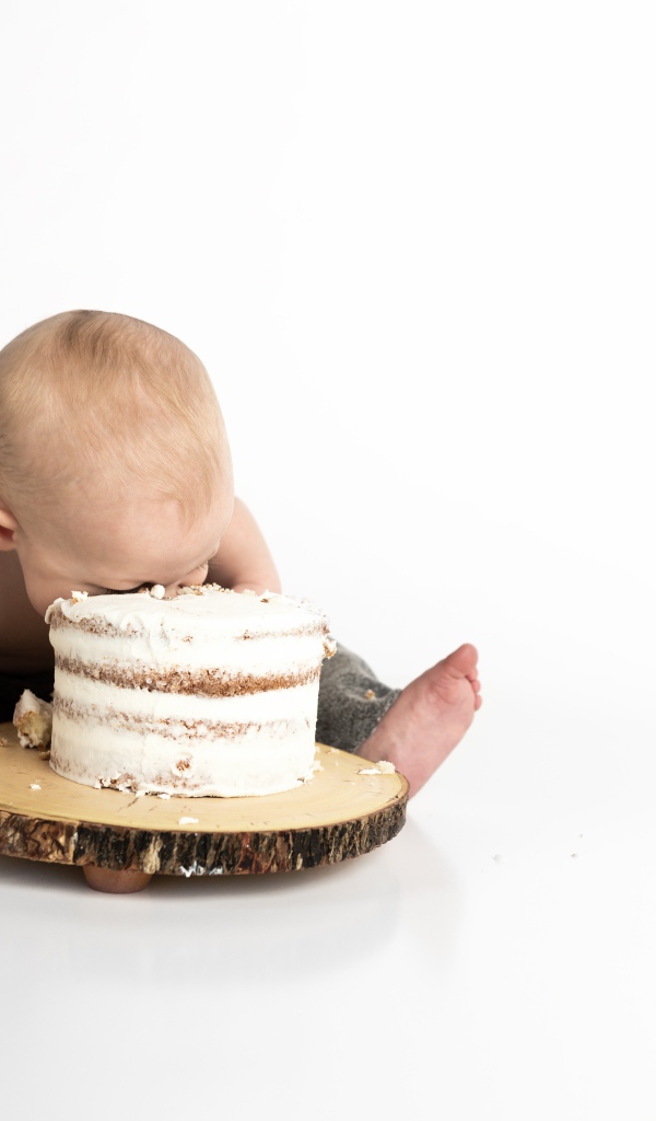 Маленький мальчик ест торт на белом фоне