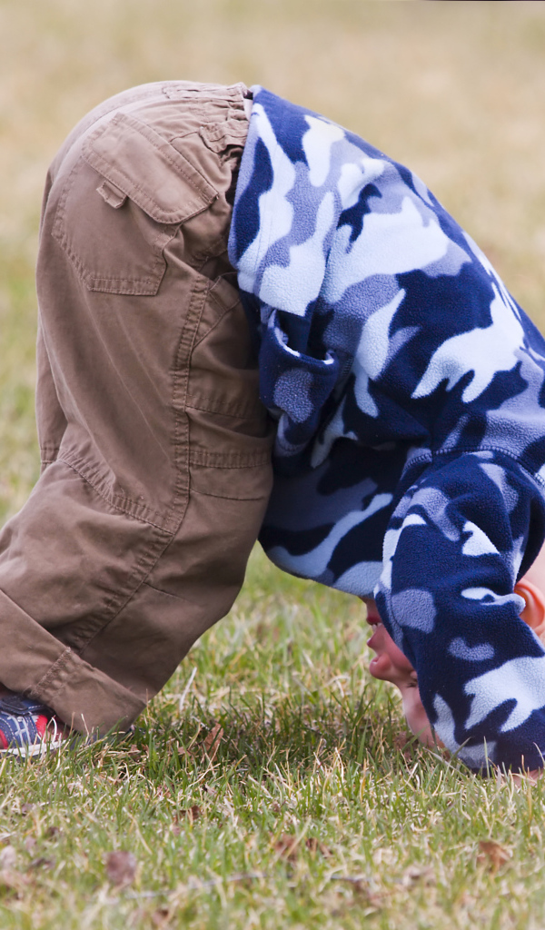 Маленький мальчик играет на траве с мячом