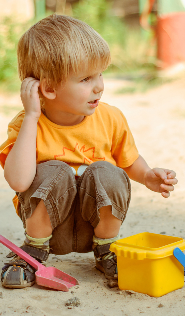 Маленький мальчик играет на песке 
