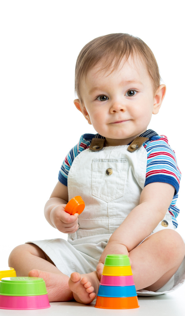 Маленький мальчик играет с пирамидкой на белом фоне