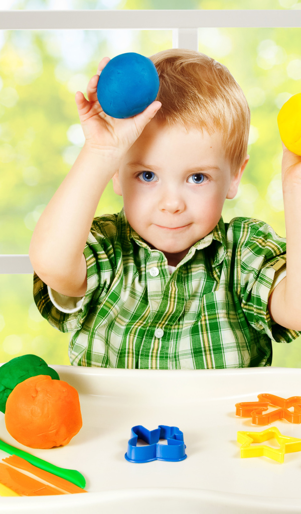 Маленький мальчик играет с игрушками у окна