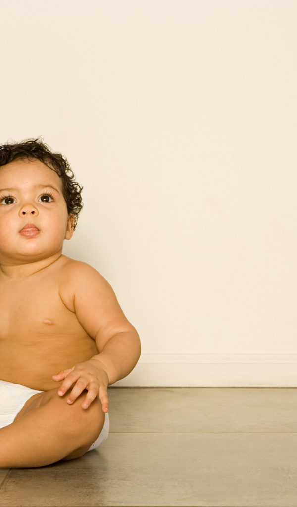 Маленький мальчик сидит на полу с игрушкой