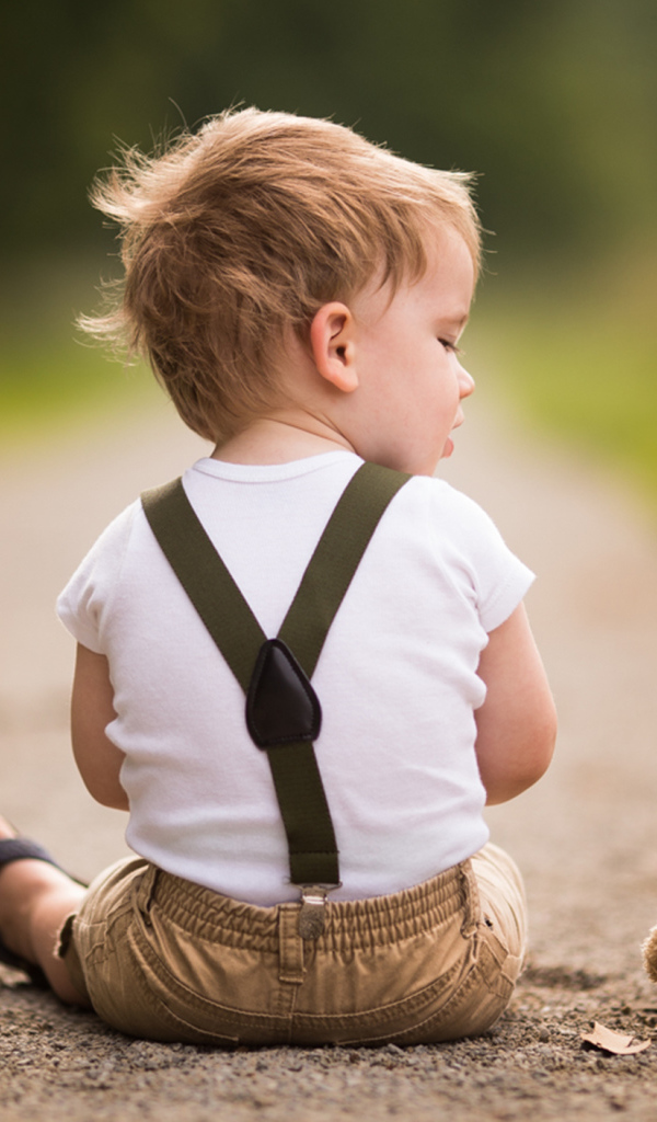 Маленький мальчик сидит на дороге с игрушечным мишкой