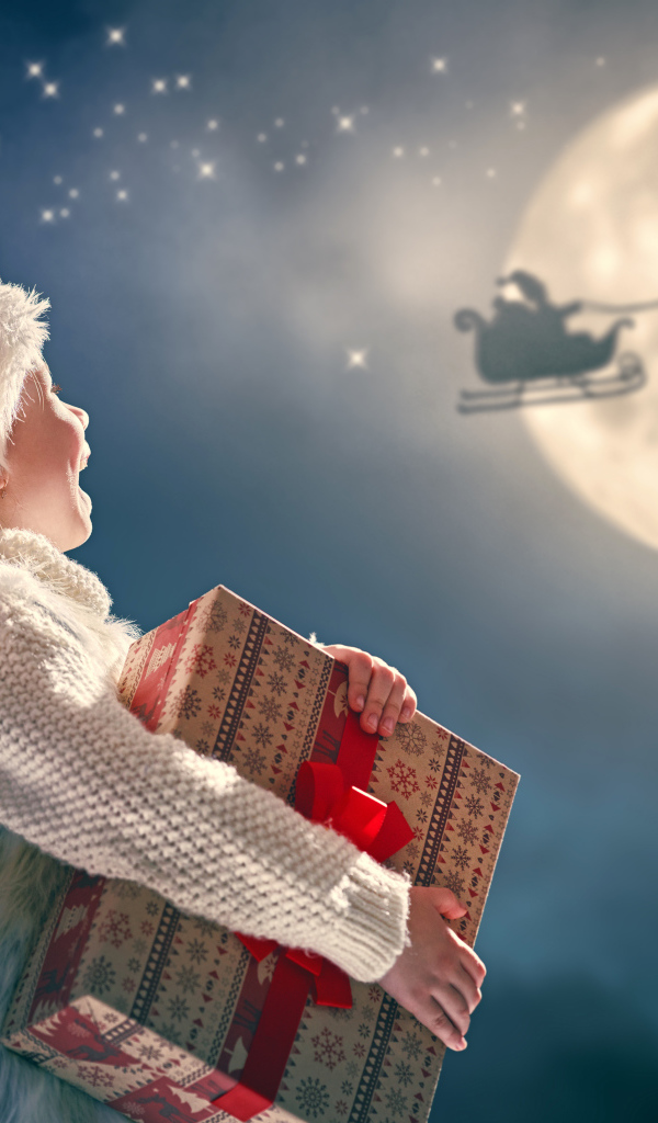 Маленький мальчик с подарком смотрит на улетающего Санта Клауса