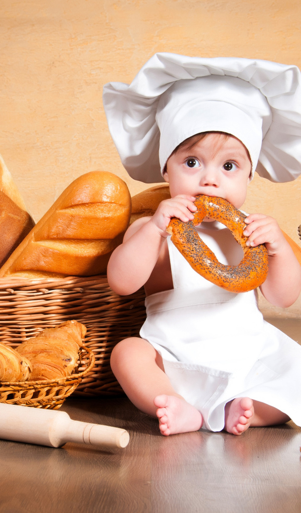 Маленький мальчик с хлебобулочными изделиями на столе 