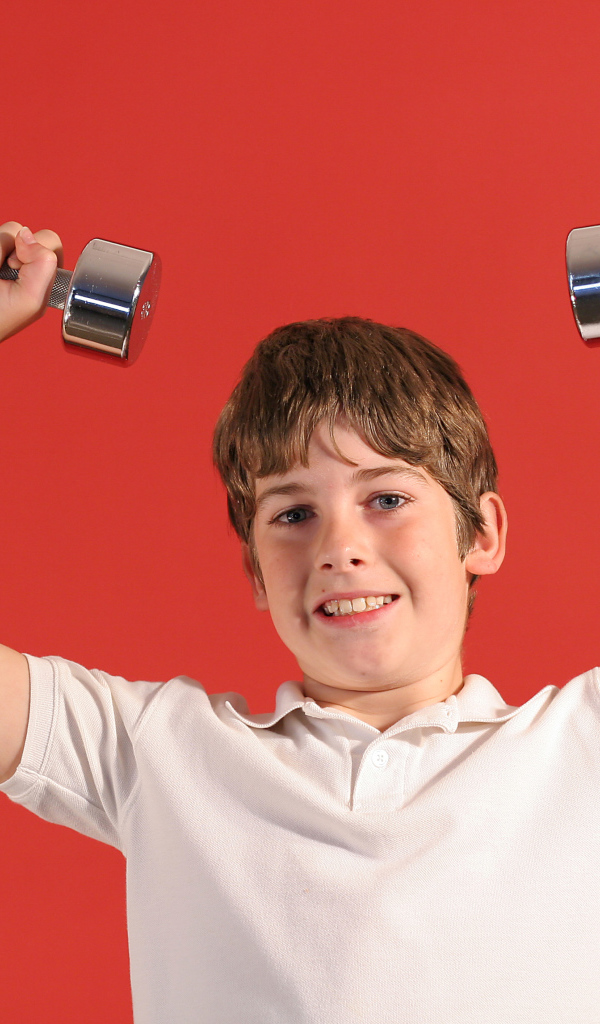 Маленький мальчик с гантелями на красном фоне