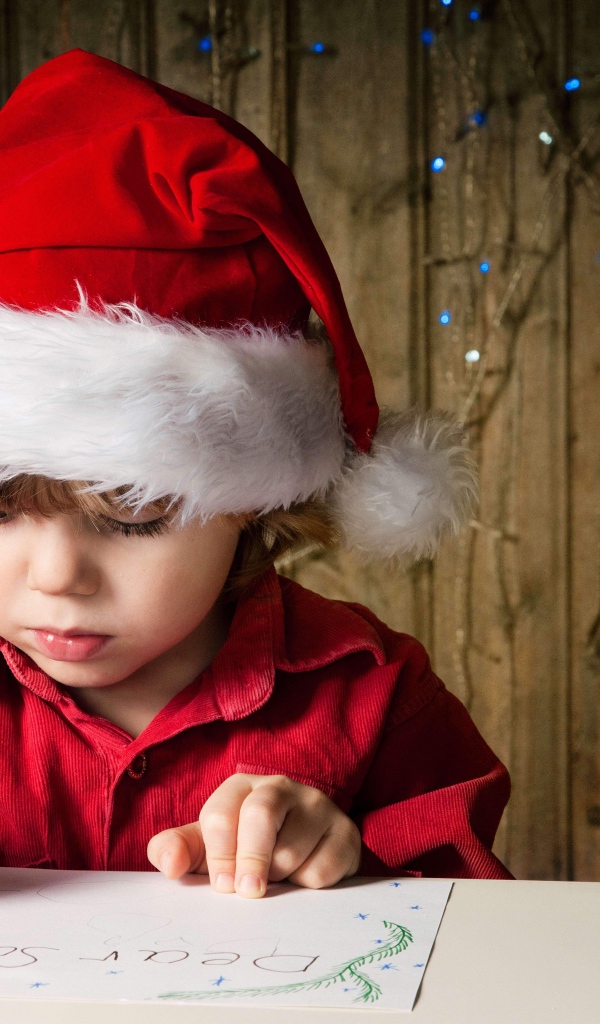 Маленький мальчик пишет письмо Деду Морозу 
