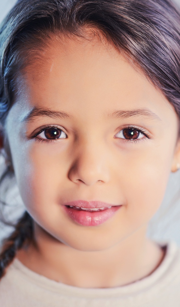 Маленькая кареглазая девочка на сером фоне