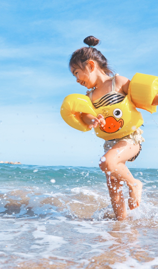 Маленькая веселая девочка бежит по морской воде