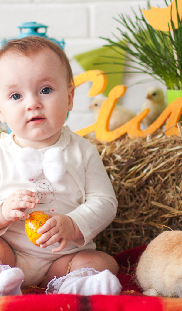 Маленький ребенок с крашеным яйцом и декоративным кроликом