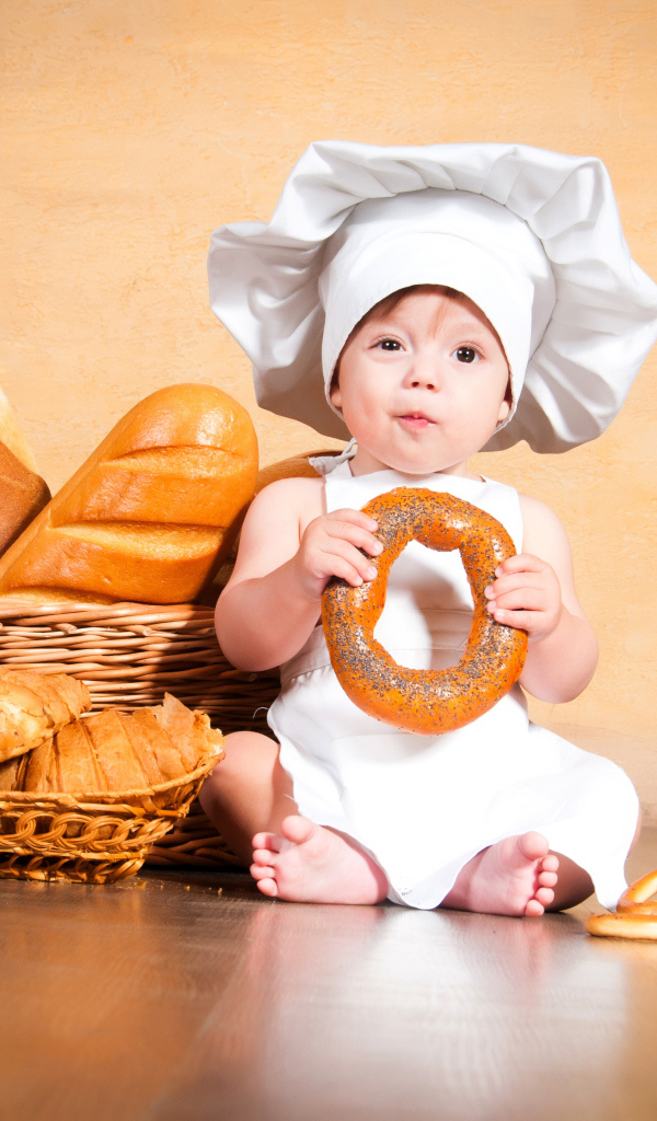 Маленький поваренок на столе со свежей выпечкой