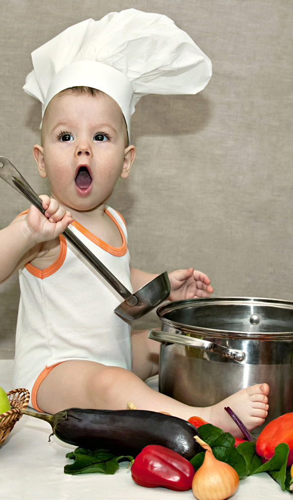 Маленький поваренок с кастрюлей на столе с овощами