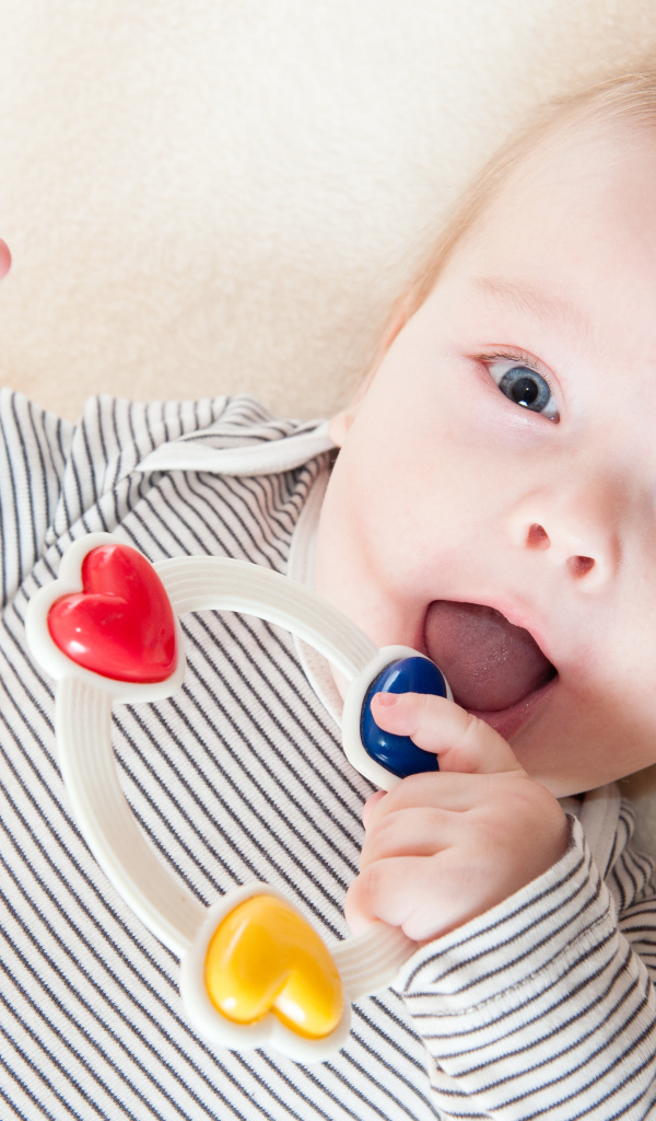 Маленький забавный голубоглазый ребенок с погремушкой