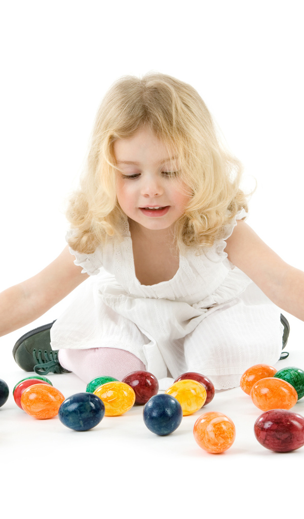 Маленькая девочка блондинка с крашеными яйцами на белом фоне