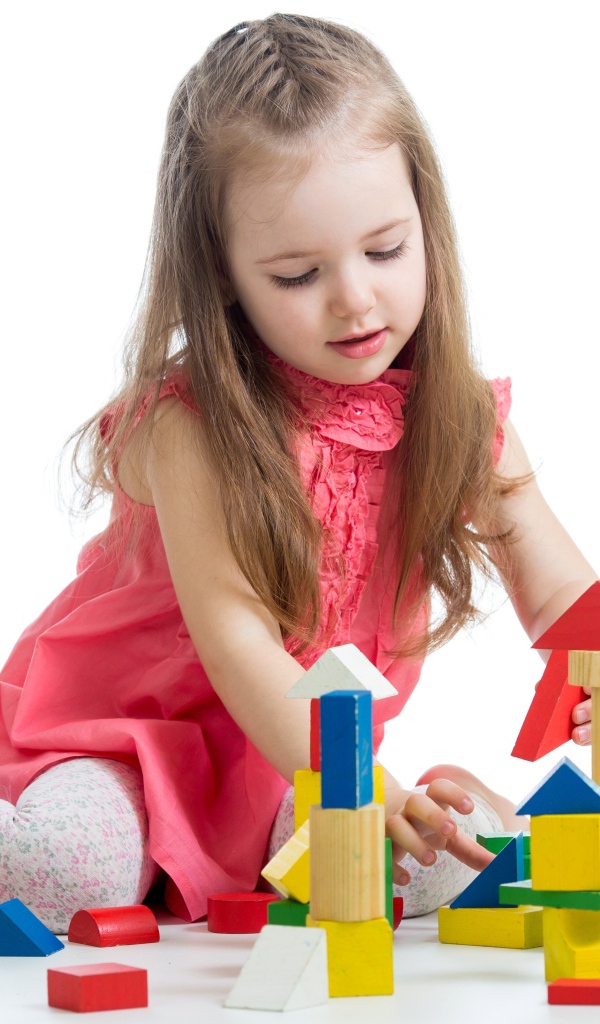 Маленькая девочка строит домик из кубиков на белом фоне