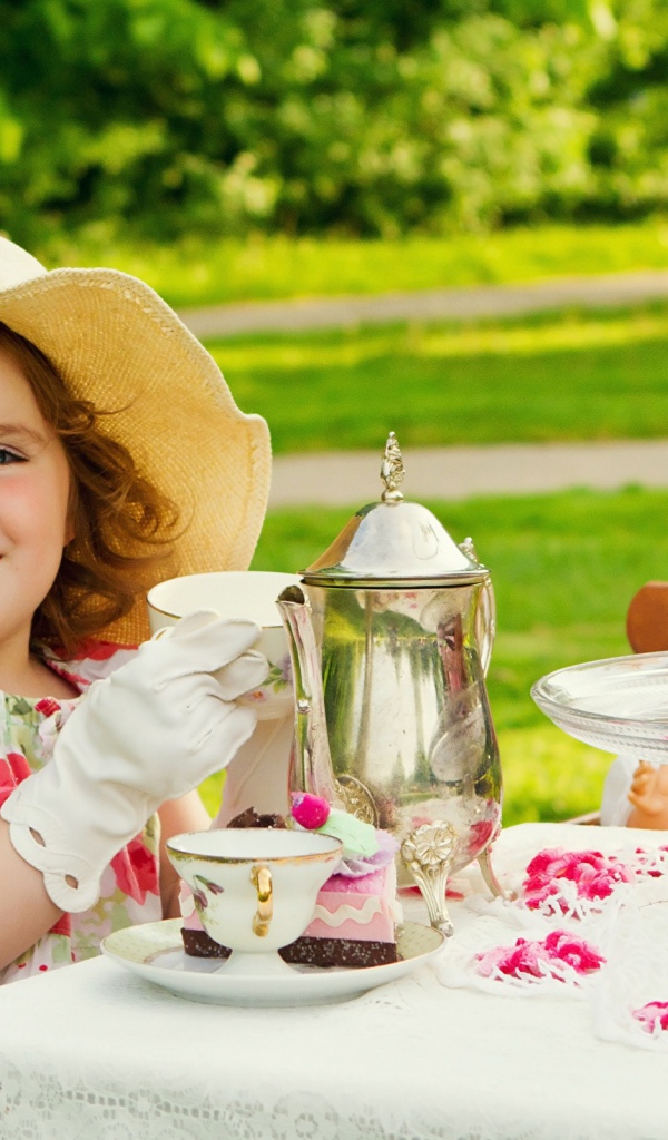 Маленькая девочка пьет чай на природе