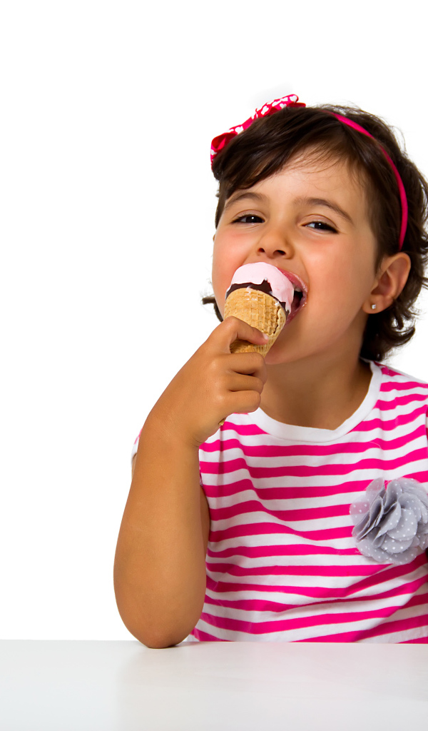 Маленькая девочка ест мороженое за столом на белом фоне