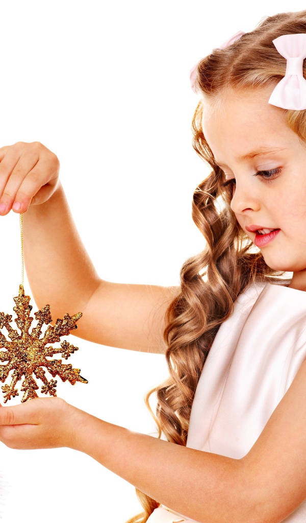 Маленькая девочка держит елочную игрушку снежинку в руке