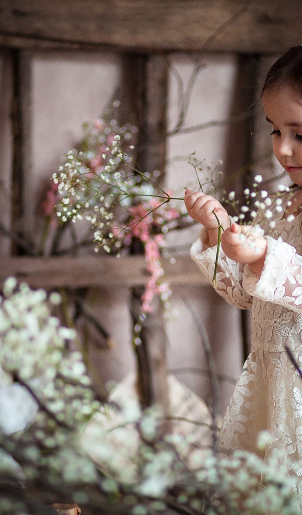 Маленькая девочка в красивом платье с белыми цветами в руке