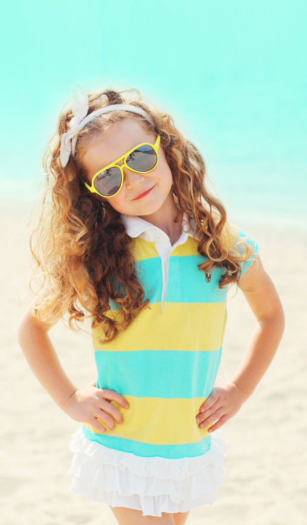 Маленькая девочка в солнечных очках на пляже