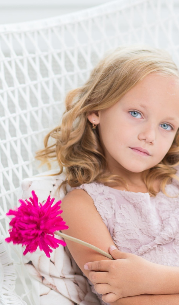 Маленькая девочка сидит в белом кресле с розовым цветком
