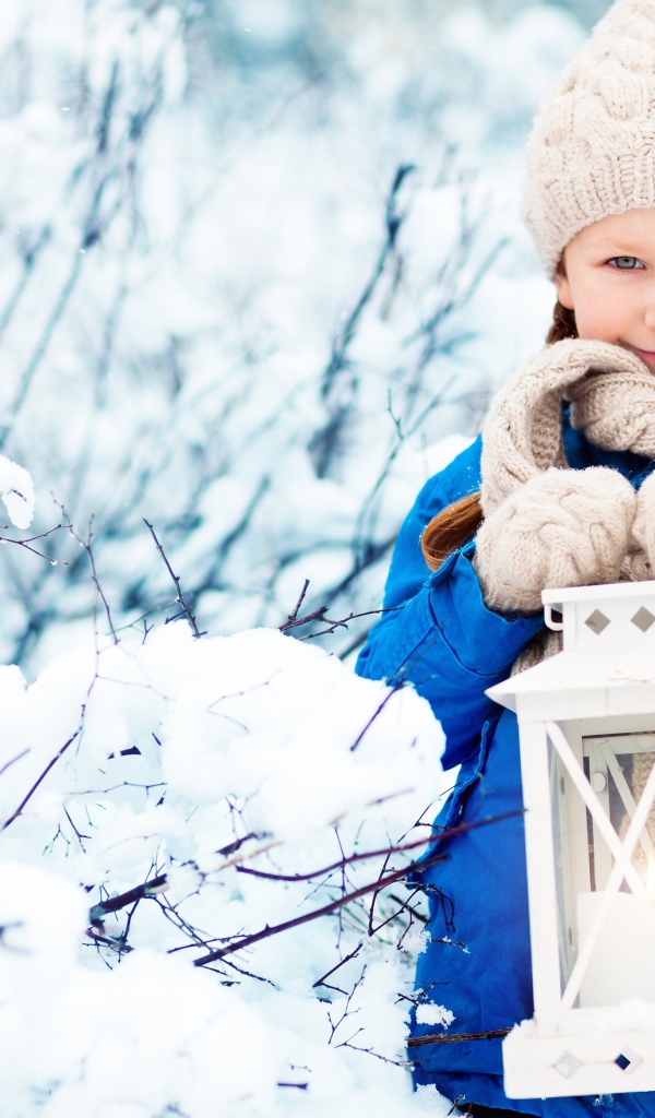 Маленькая девочка с фонарем на улице зимой