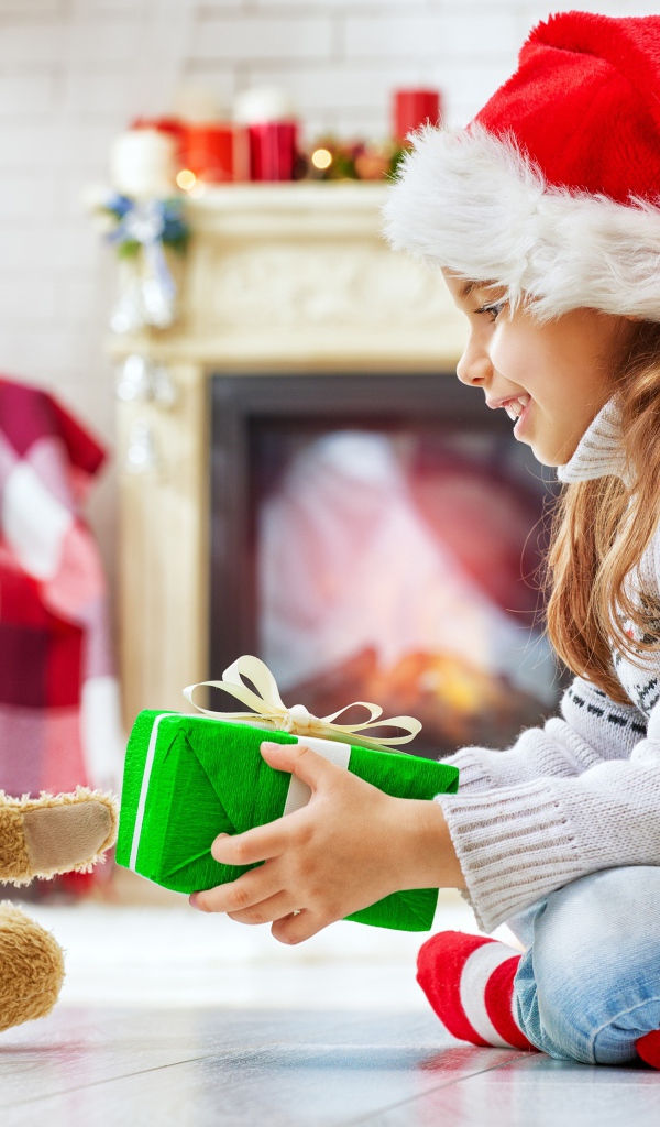 Маленькая девочка с медвежонком Тедди у елки с подарками на Новый год