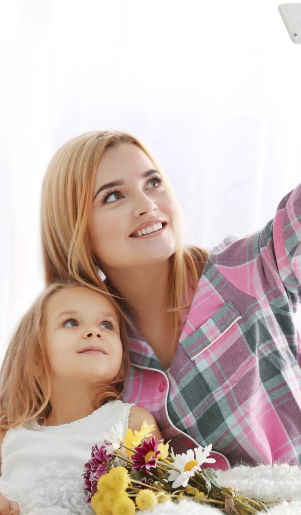 Маленькая девочка с мамой делают фото на смартфон