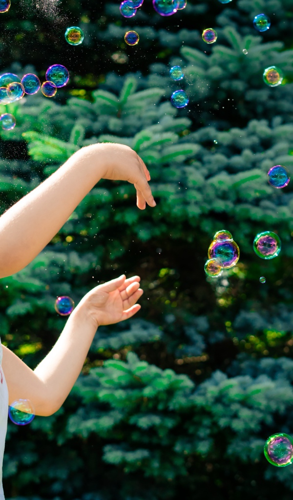 Маленькая девочка с мыльными пузырями у елки