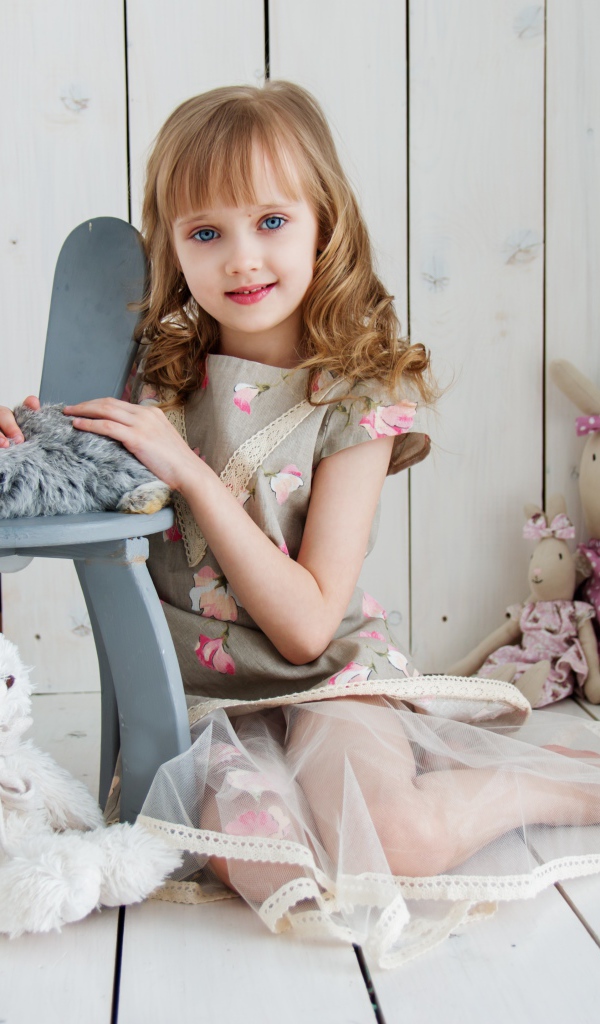 Маленькая девочка с игрушками в комнате сидит на полу