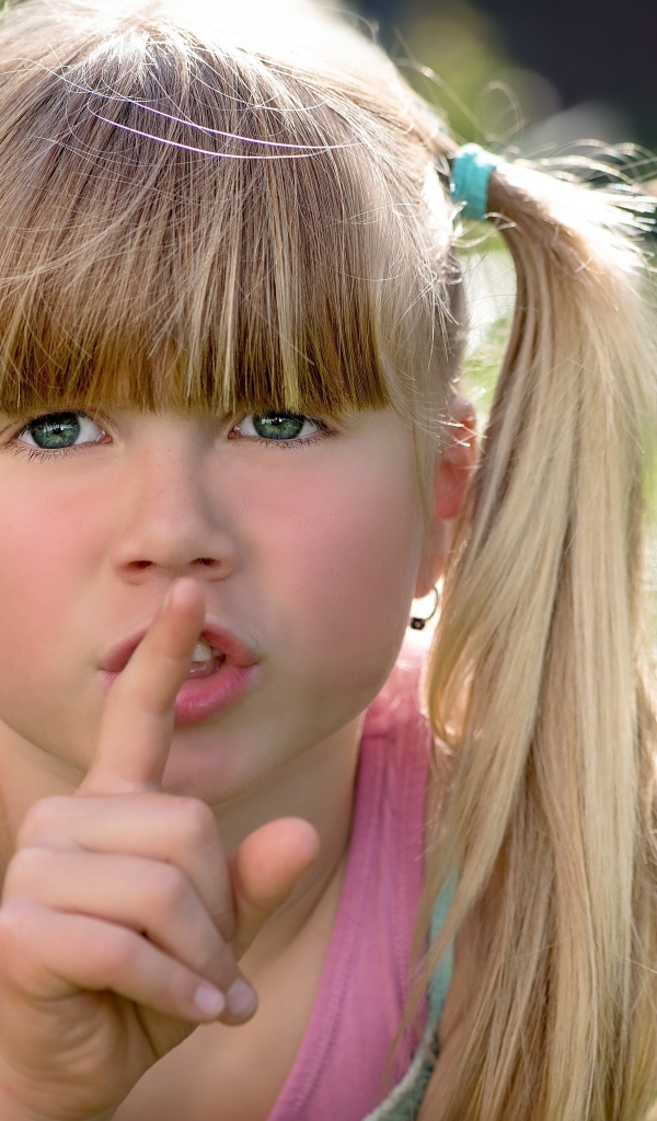 Маленькая зеленоглазая девочка с пальцем у рта 