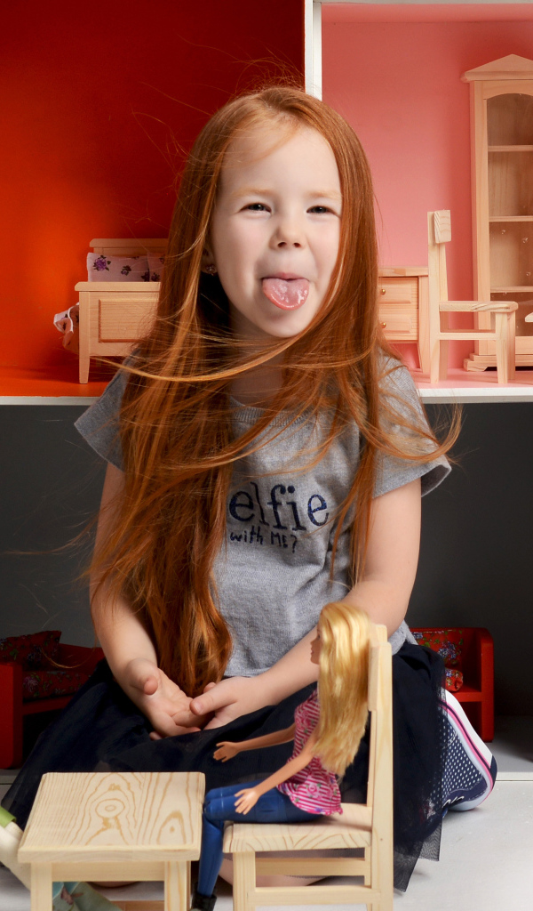 Маленькая длинноволосая девочка показывает язык