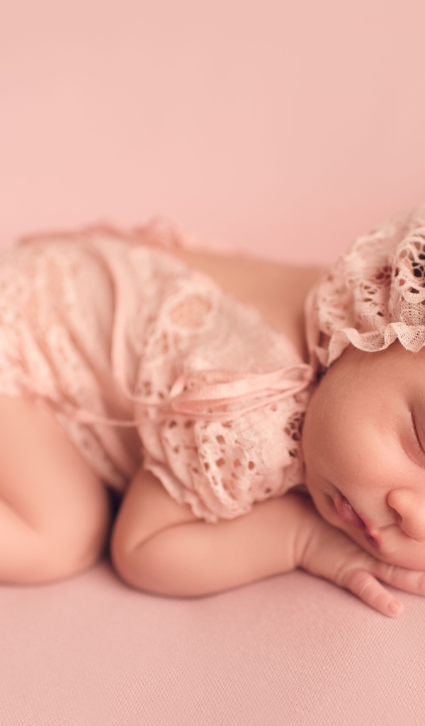 Маленькая новорожденная девочка в розовом костюме 