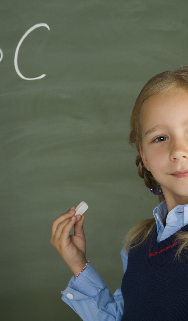 Маленькая школьница пишет буквы на доске 