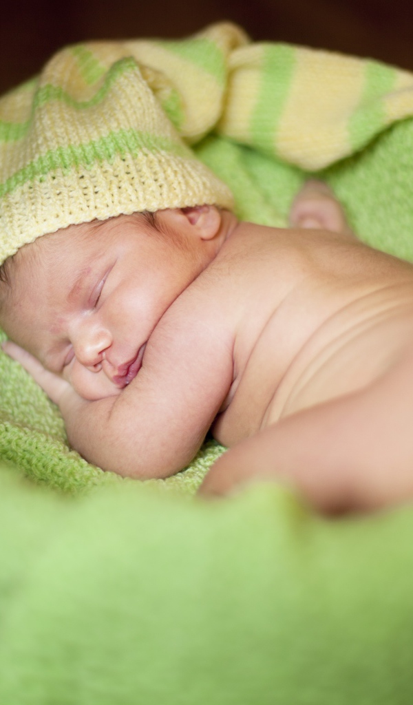 Маленький спящий грудной ребенок на зеленом покрывале 