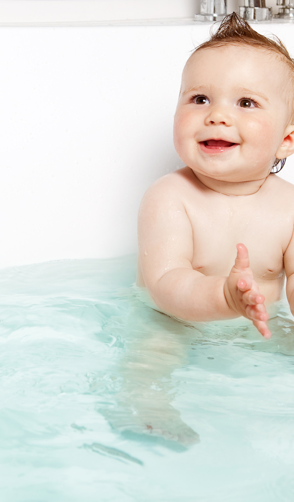 Маленький улыбающийся ребенок с игрушками в ванной 