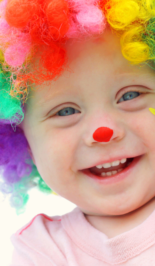 Маленький улыбающийся мальчик в костюме клоуна на белом фоне