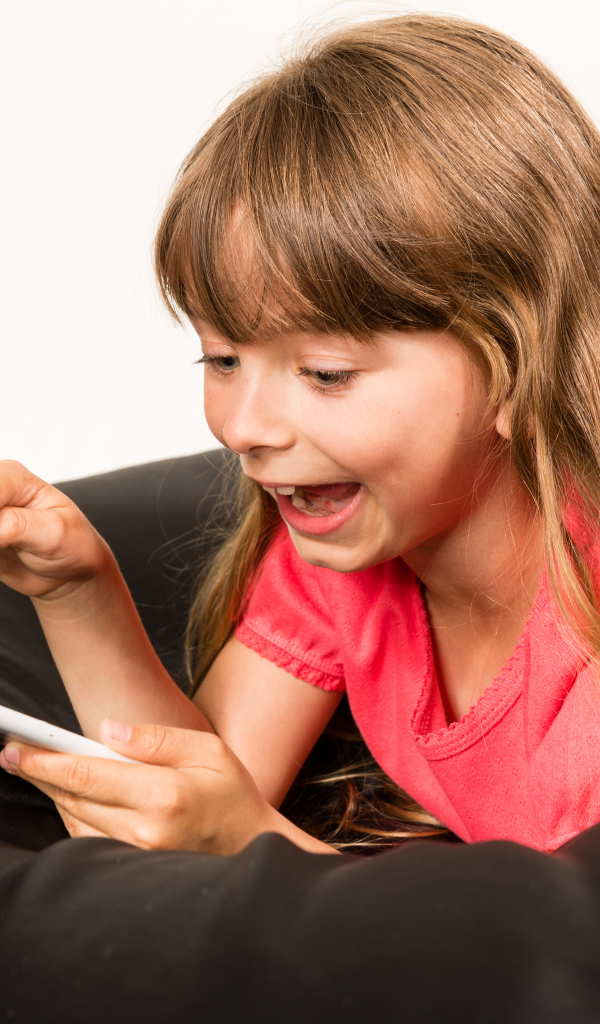 Маленькая улыбающаяся девочка лежит с планшетом