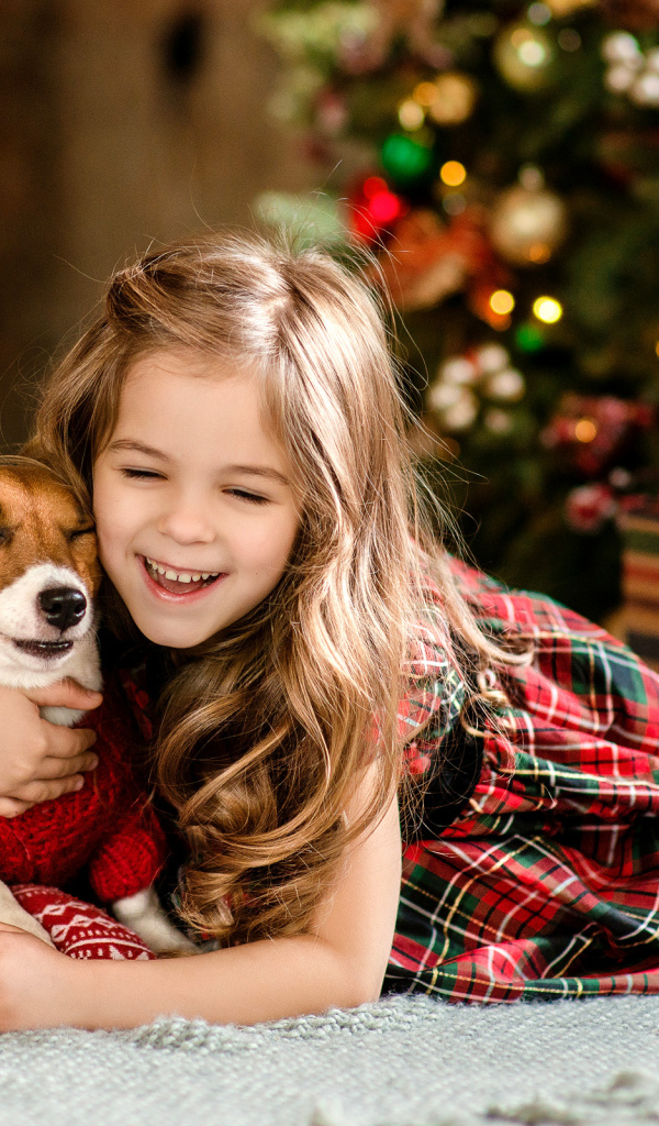 Веселая девочка с собакой у елки 
