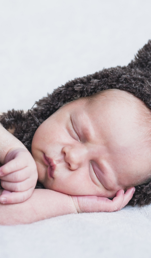 Спящий грудной ребенок в меховой шапке