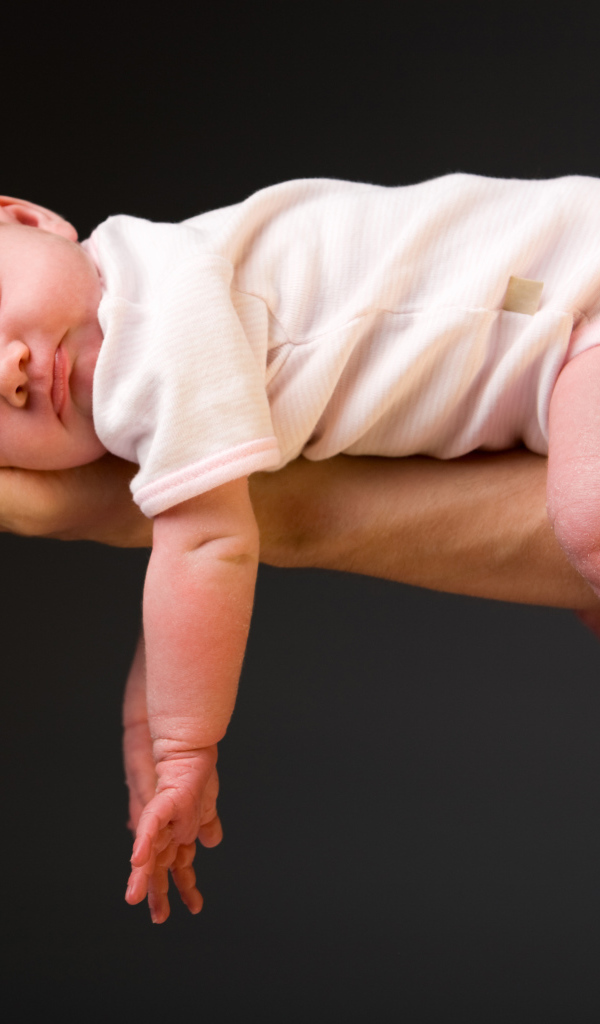 Спящий ребенок на руке у папы на сером фоне