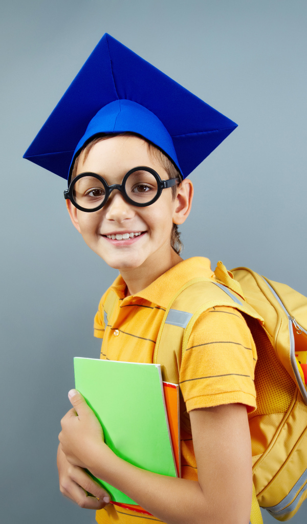 Умный школьник в очках со школьными принадлежностями на сером фоне